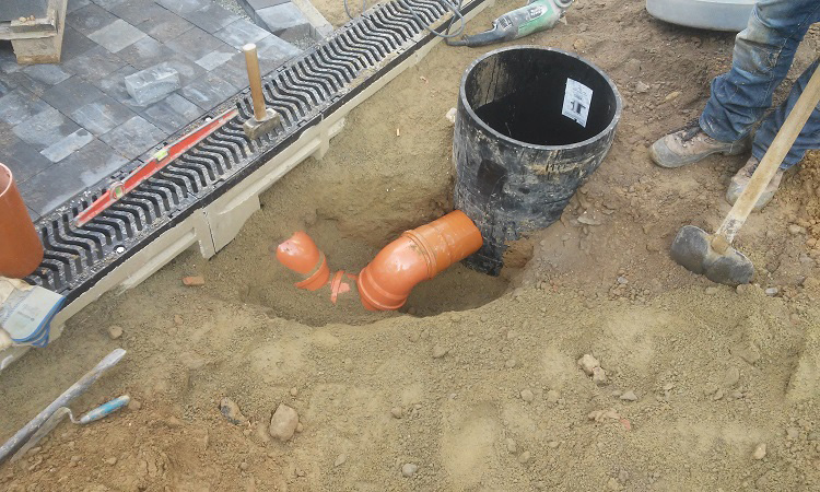 Raccordement d'un caniveau au réseaux d’égouttage. Pose d'un siphon pour eviter les odeurs